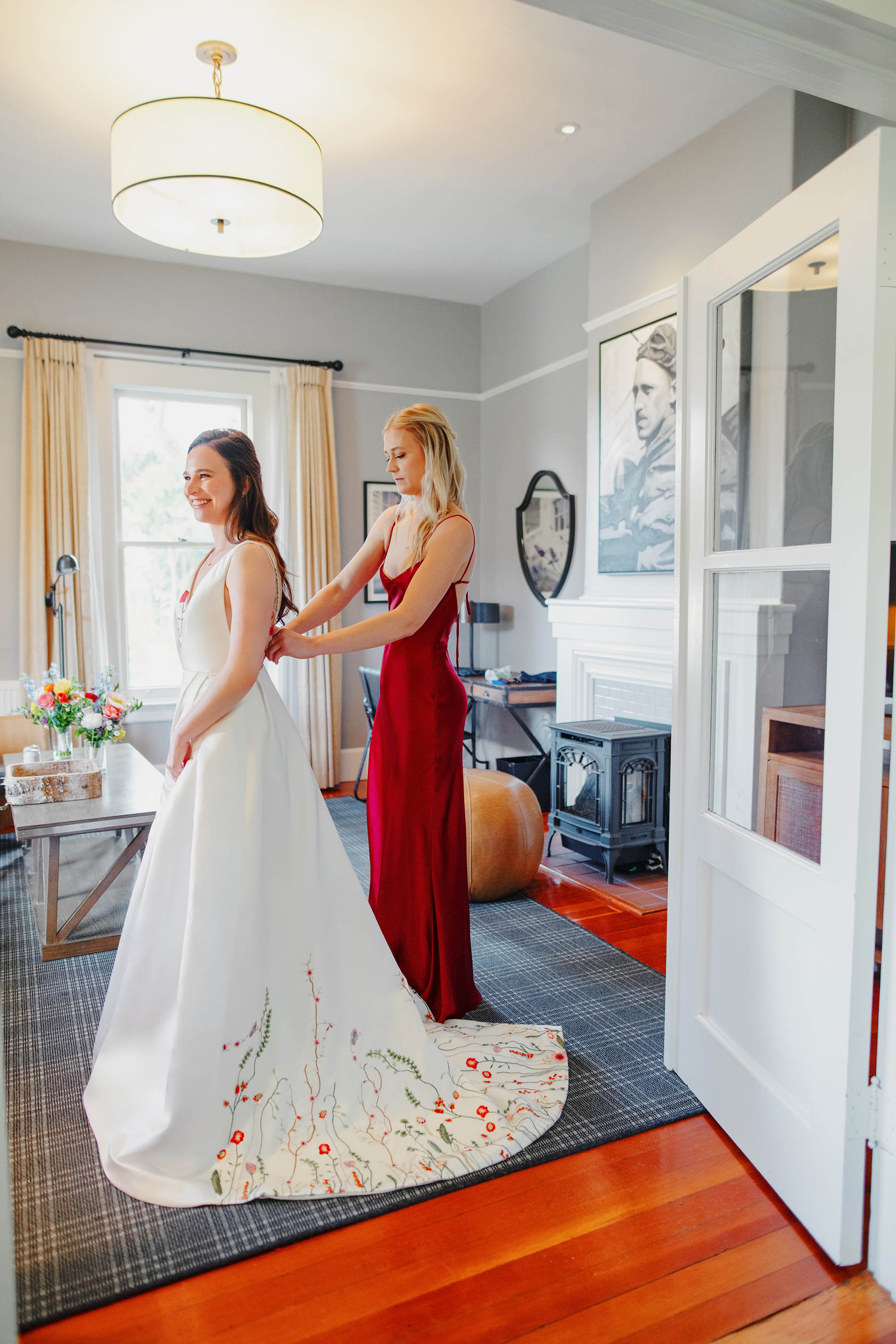 beautiful getting ready photo of bride putting on her wedding dress with the help of her maid of honor