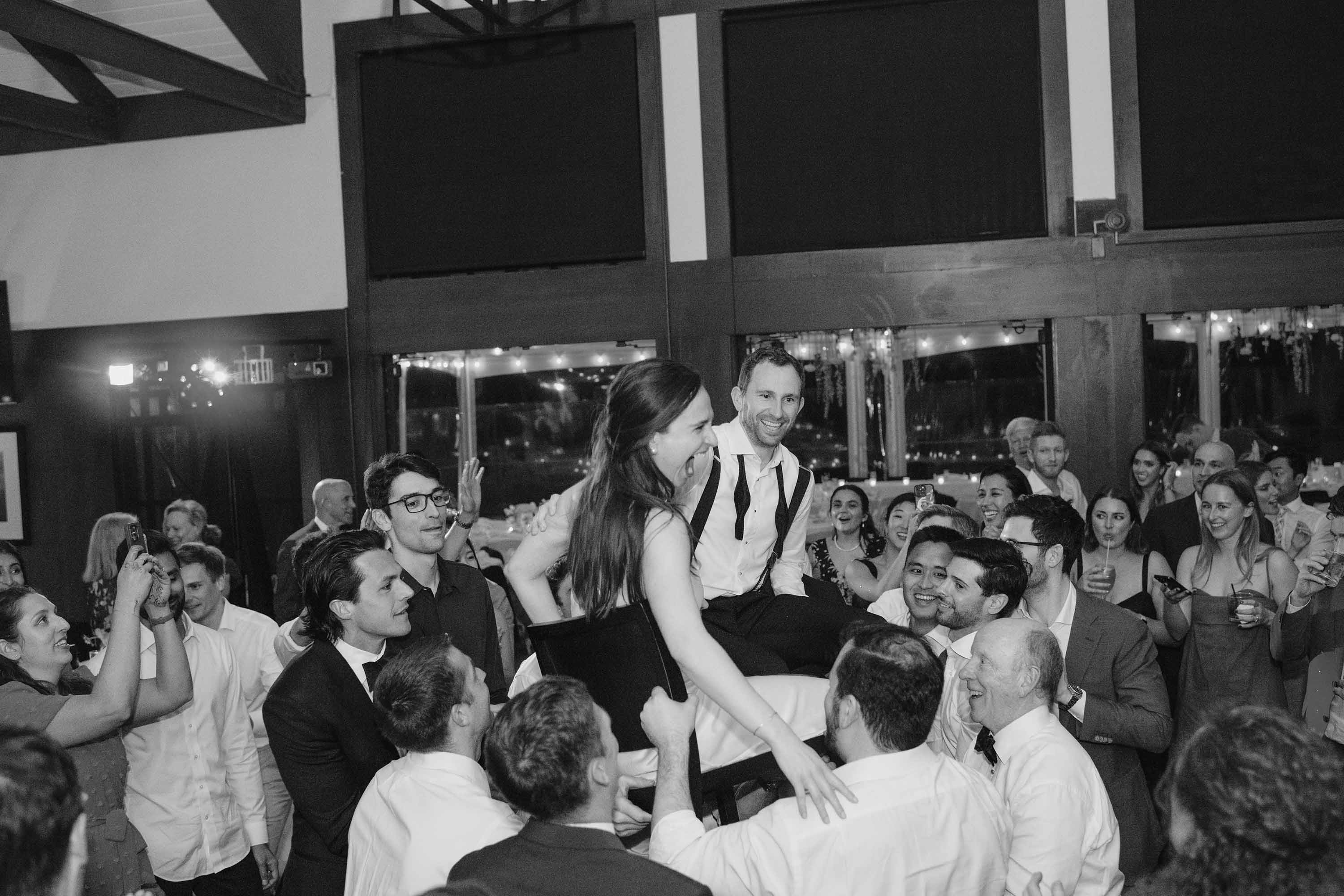 Bride and groom get lifted high into the air during their wedding reception. Credit: Love Knot Photography by Isaac Klotz