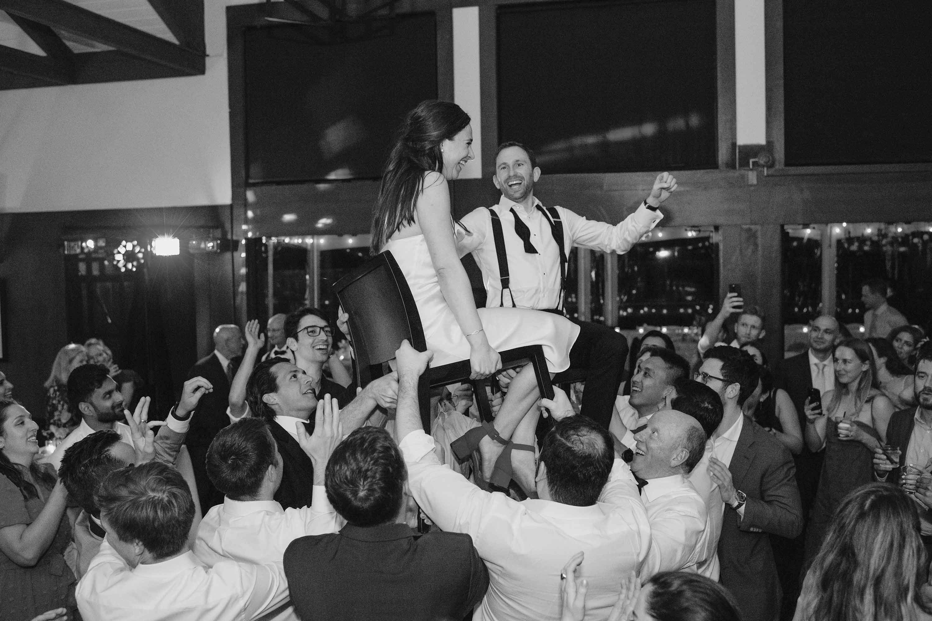 Candid chair dance photo as the bride and groom enjoy the chaos of the moment during their reception. Credit: Love Knot Photography by Isaac Klotz