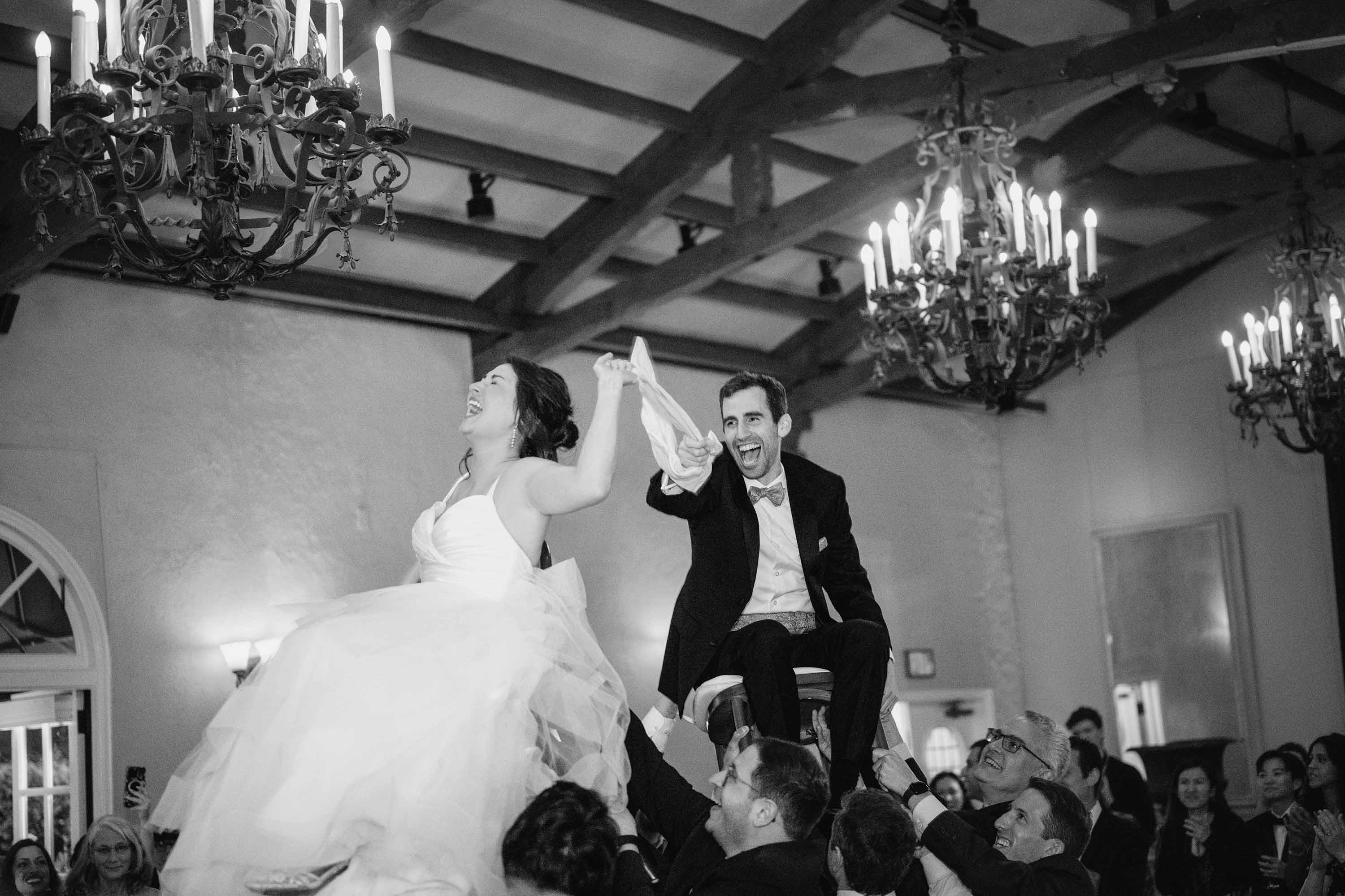 bride and groom during the hora as their are lifted high in chairs