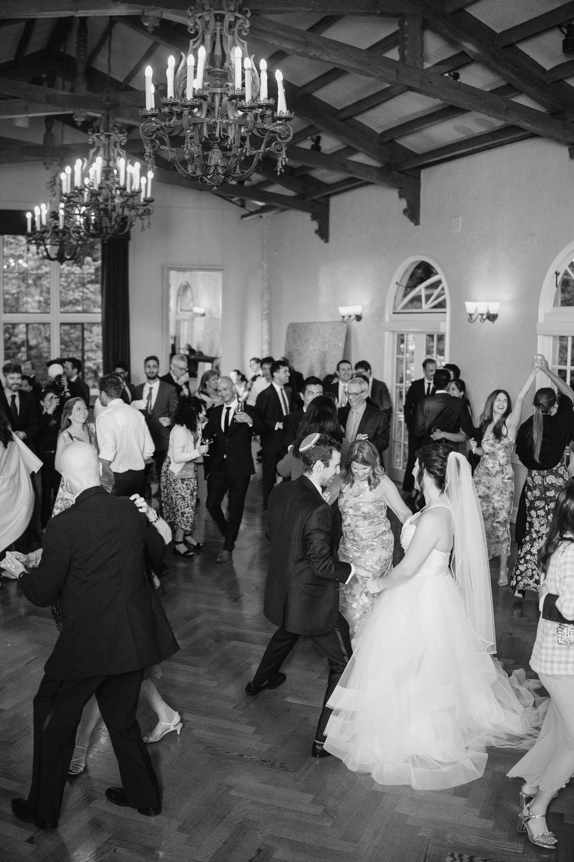 candid black and white photo of bride and groom with everyone on the dance floor